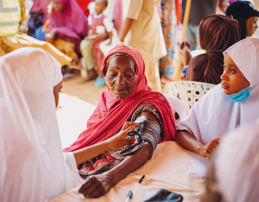 An outdoor health checkup for the elderly in Kaduna, Nigeria, emphasizing community care.
